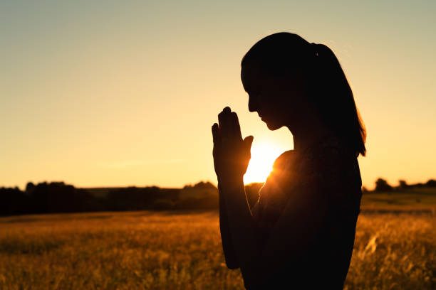 istock Woman praying at sunset. 1719076414