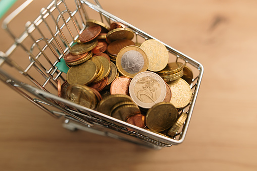 A small shopping cart filled with coins