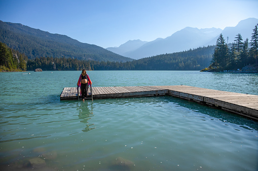 With her pregnant belly exposed, she dips her toes into the glacial water. \nAt Green Lake, in Whistler, BC