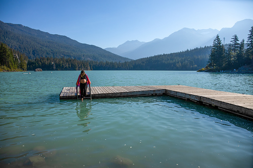 With her pregnant belly exposed, she dips her toes into the glacial water. 
At Green Lake, in Whistler, BC