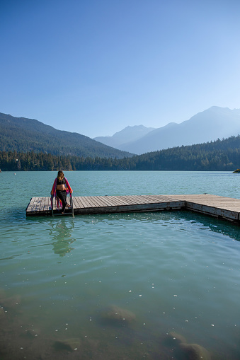 With her pregnant belly exposed, she dips her toes into the glacial water. \nAt Green Lake, in Whistler, BC