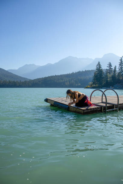 istock Young woman relaxes on lakeside dock in the morning 1719084762