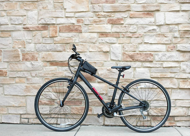Black Hybrid Bicycle Against Tan Flagstone Wall stock photo