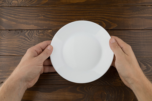 Hands hold an empty white plate