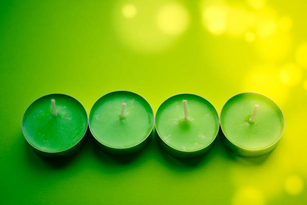 Four low new green candles on lime table. Top view.