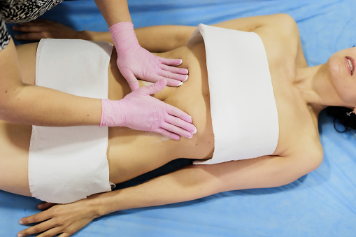 woman in slimming abdominal massage treatment with gel. Cosmetology and massage concept.