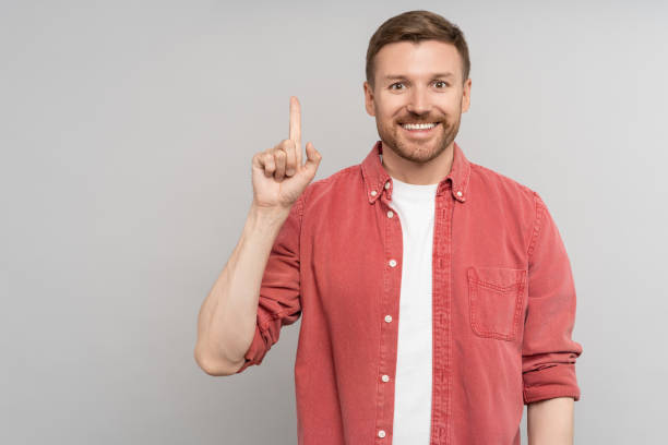 istock Handsome pleased guy with idea gesture showing direction with finger up for ad on studio background 1719174665