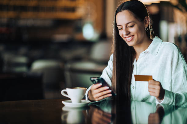 istock A happy brunette is sitting in a cafe and using her phone and credit card 1719175251