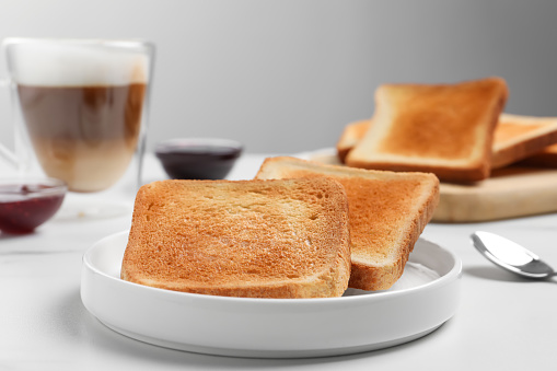 Slices of tasty toasted bread on white table, closeup
