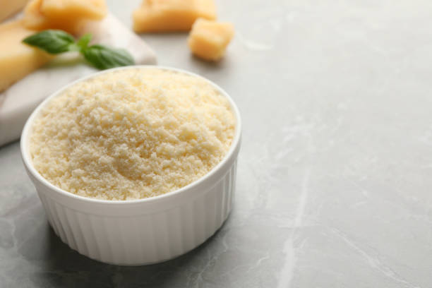 istock Bowl with grated parmesan cheese on light marble table, closeup. Space for text 1719193570
