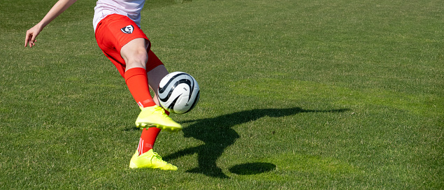 Soccer female player leg kicking sports ball during match on field