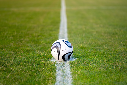 Football ball on white marking halfway line on field close up selective focus