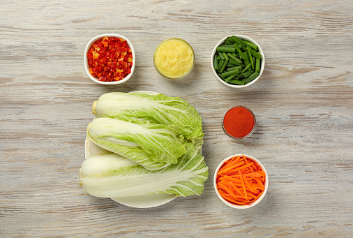 Fresh Chinese cabbages and other ingredients for kimchi on wooden table, flat lay