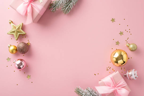 istock Luxurious Festive Atmosphere inspiration. Top view of gift boxes adorned with bows, delightful tree decor, glimmering stars, sequins, frosty spruce branches on pastel pink backdrop for your text or ad 1719213020