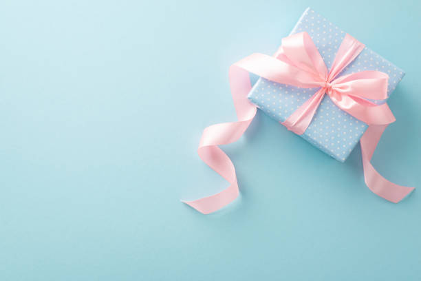 wysyłanie uśmiechów: widok z góry pastelowego niebieskiego pudełka upominkowego, jego wzór w kropki i różowa wstążka promieniująca szczęściem. pastelowe niebieskie tło czeka na twój osobisty akcent - gift pink box gift box zdjęcia i obrazy z banku zdjęć