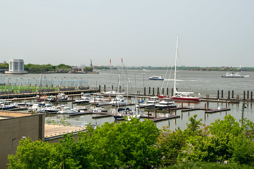 A picturesque scene in Brooklyn Heights, NY, USA, featuring a charming pier adorned with boats and elegant sailing yachts, set against a scenic waterfront backdrop.