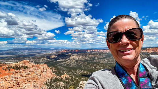 This woman is taking a selfie in front of some dramatic landscape