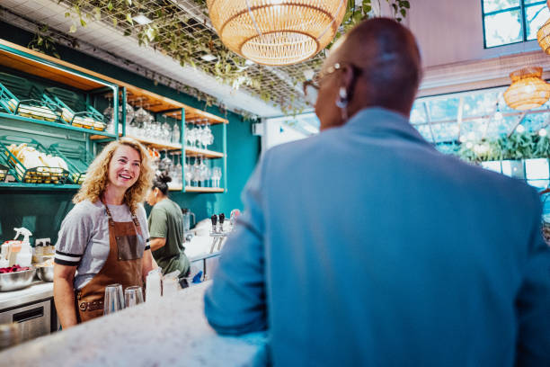 Mature waitress talking to customer on coffee shop