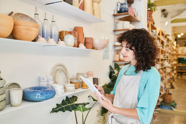 istock Woman using a digital tablet while taking inventory of ceramic products in her local pottery workshop. 1719255151