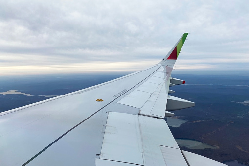 A photograph capturing the wing of a TAP Air Portugal airplane against the backdrop of the clear Lisbon sky, showcasing the excitement of travel.