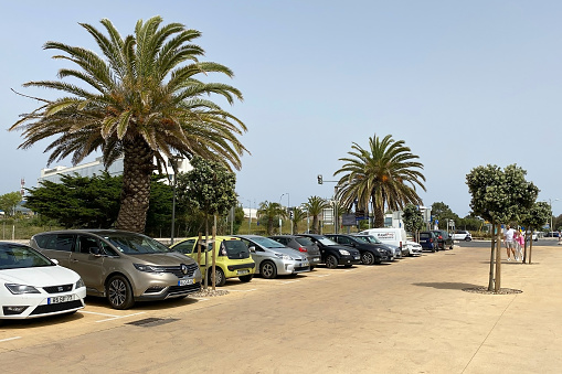 A car parked near the picturesque Cascais beach in Lisbon, Portugal, with golden sands and the sparkling sea in the background.