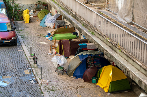 A homeless tent camp in Lisbon, Portugal, nestled within the historic heart of the city, where individuals in need have set up makeshift shelters.