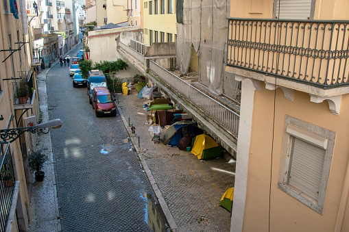 A homeless tent camp in Lisbon, Portugal, nestled within the historic heart of the city, where individuals in need have set up makeshift shelters.