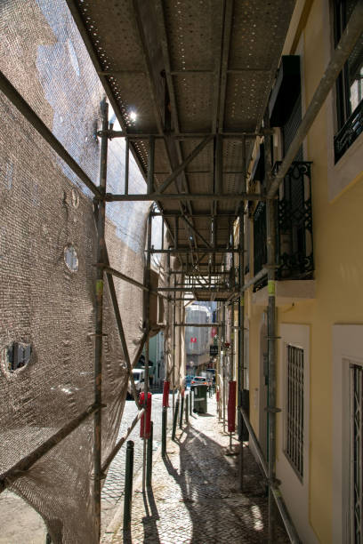 lissabon, portugal, rekonstruktion der fassade eines historischen mehrfamilienhauses an einer stadtstraße, fassadenbaugewebe deckt ein altes haus ab, das für die renovierung geschlossen wurde wand außen - restoring house scaffolding history stock-fotos und bilder