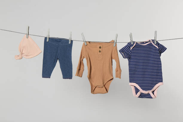istock Different baby clothes drying on laundry line against light background 1719282911