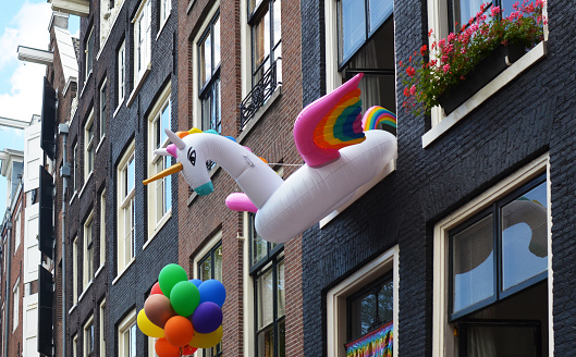 Inflatable unicorn ring and rainbow balloons on building facade. LGBT pride concept
