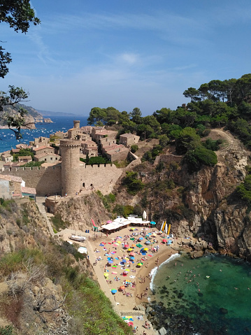 A breathtaking sea view of Tossa de Mar in Girona, Spain, featuring a picturesque beach with people enjoying the stunning coastal landscape.