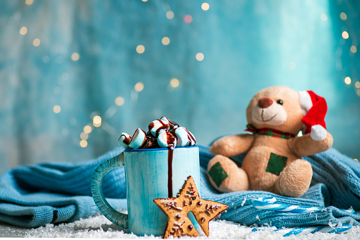 Warm marshmallow drink and a cookie dessert set with festive Christmas and New Year symbols on a decorated table with festive background