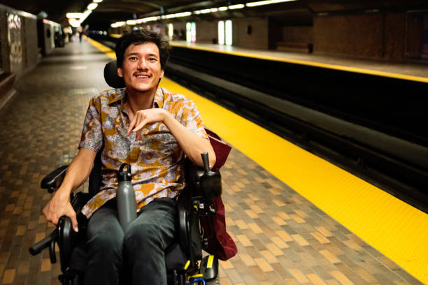 Young asian man using a wheelchair in a subway station.