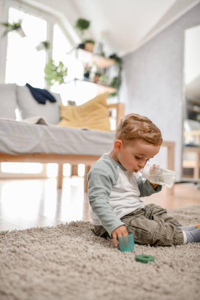 istock Baby Boy Drinking Water And Playing On The Carpet 1719328587