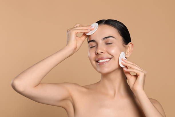 istock Young woman using cotton pads with micellar water on beige background 1719330231