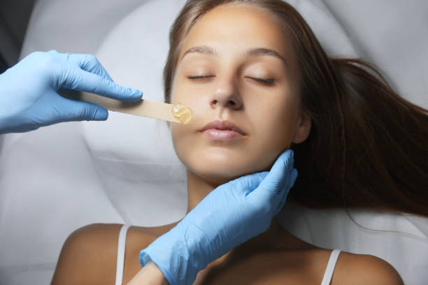 istock Young woman undergoing hair removal procedure on face with sugaring paste in salon 1719353656