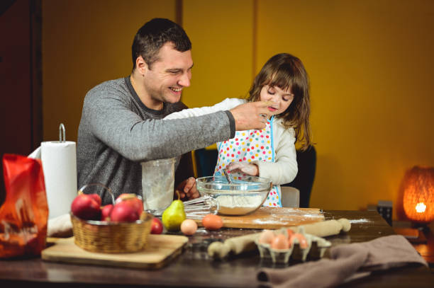 istock smiling father playing with his daughter while cooking an autumn apple pie. 1719355910