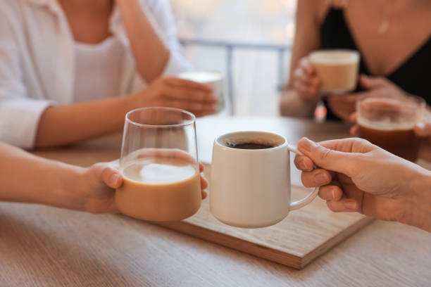 istock Friends drinking coffee at wooden table in cafe, closeup 1719364862