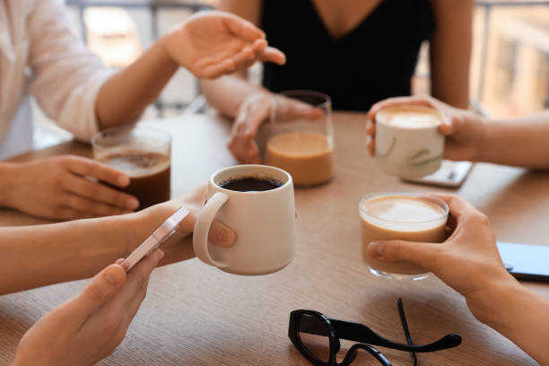 istock Friends drinking coffee at wooden table in cafe, closeup 1719365893