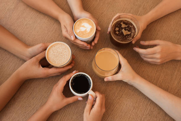 istock Friends drinking coffee at wooden table in cafe, top view 1719365906