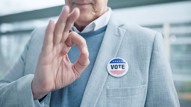 Pointing, ok hand and a person with a badge for election, government change and politics. Closeup, showing and a man with a tag or pin for promotion of campaign or voting with a perfect gesture