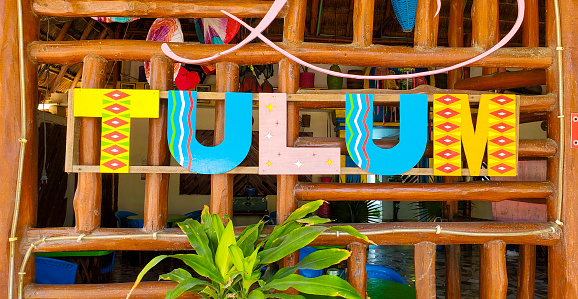 In Tulum, Mexico hand painted wooden letters marking the location are hanging outside the exterior of a cafe with rustic wooden railing.