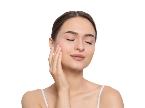 istock Young woman applying cream under eye on white background 1719443405