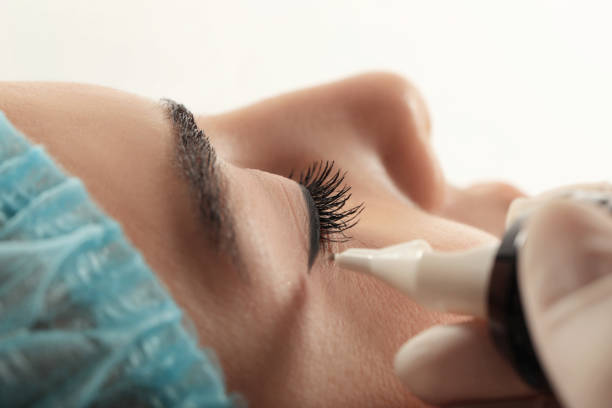 istock Young woman undergoing procedure of permanent eyeliner makeup on white background, closeup 1719450829