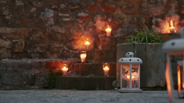 Burning candles placed on the steps of the stairs of a European old town. Wedding or reception decoration during blue twilight or evening.