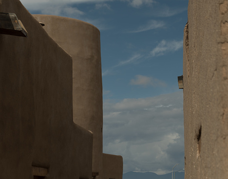 Narrow pass between tall adobe buildings on a plaza near Santa Fe, New Mexico