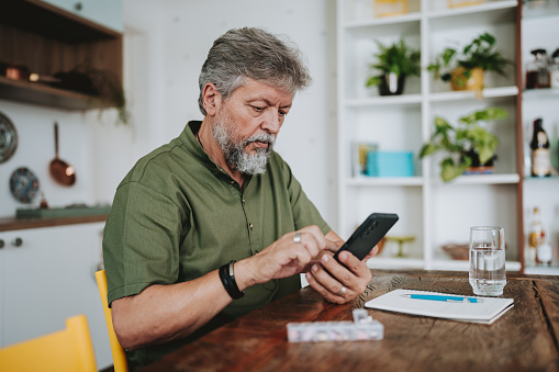 Elderly man checking medical prescription on smartphone