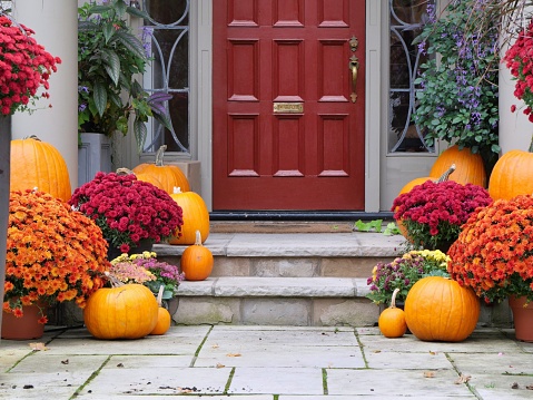 Front steps of house with fall decorations, flowers and pumpkins