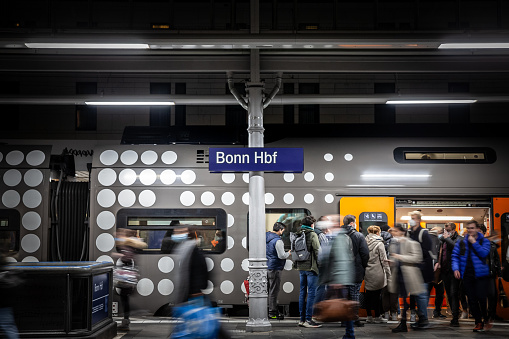 Picture of the Bonn Hbf platform concourse with people rushing in a crowd in Cologne, Germany. Bonn Hauptbahnhof is a railway station located on the left bank of the Rhine along the CologneMainz line. It is the principal station serving the city of Bonn. In addition to extensive rail service from Deutsche Bahn it acts as a hub for local bus, tram, and Stadtbahn services.