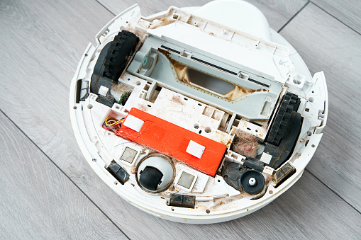 Repairing a robot vacuum cleaner that is clogged with dirt and hair. Disassembled robot vacuum cleaner. the concept of repairing home electronics